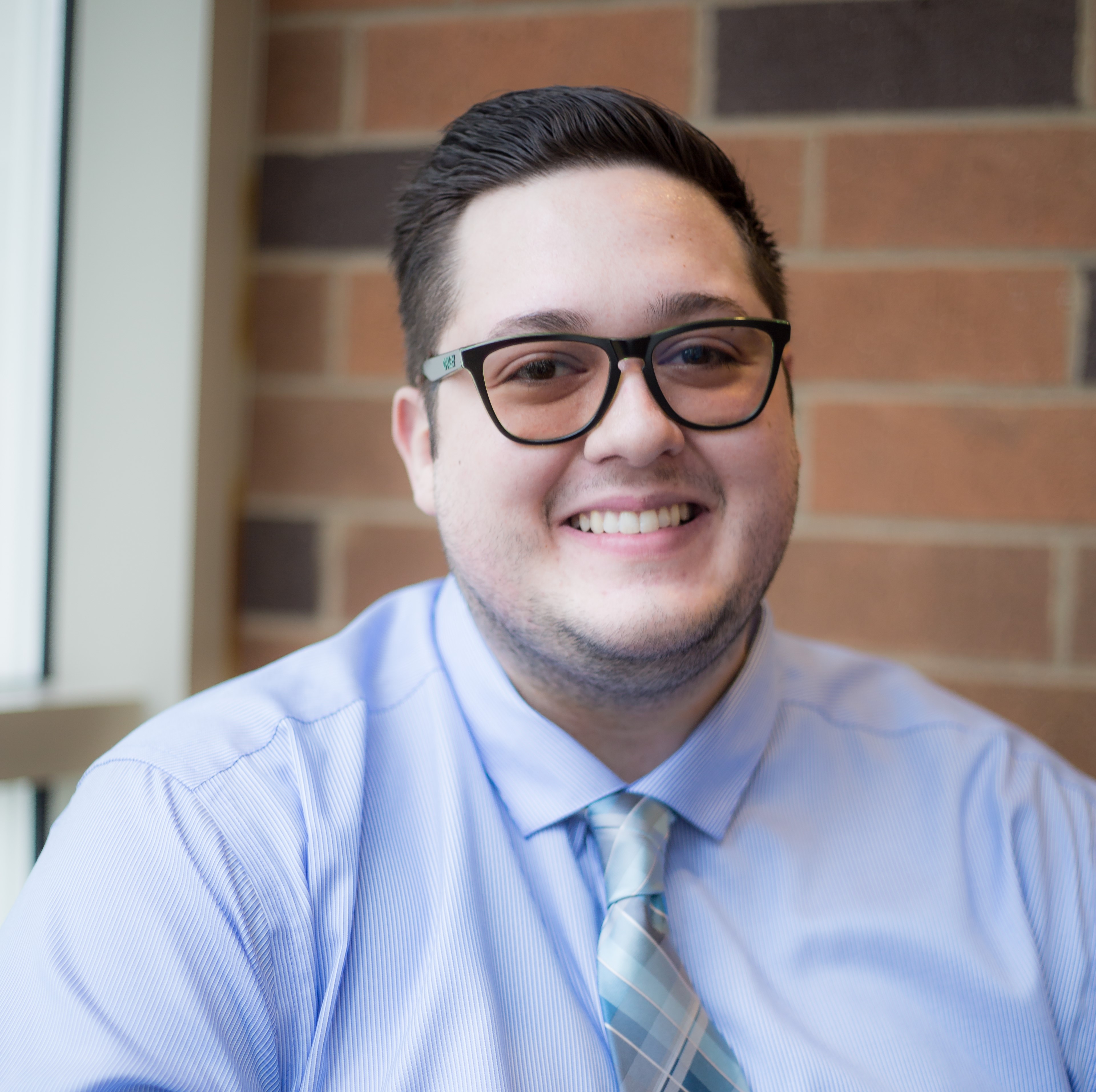 Headshot of Austin J. Foglesong in front of a brick wall.