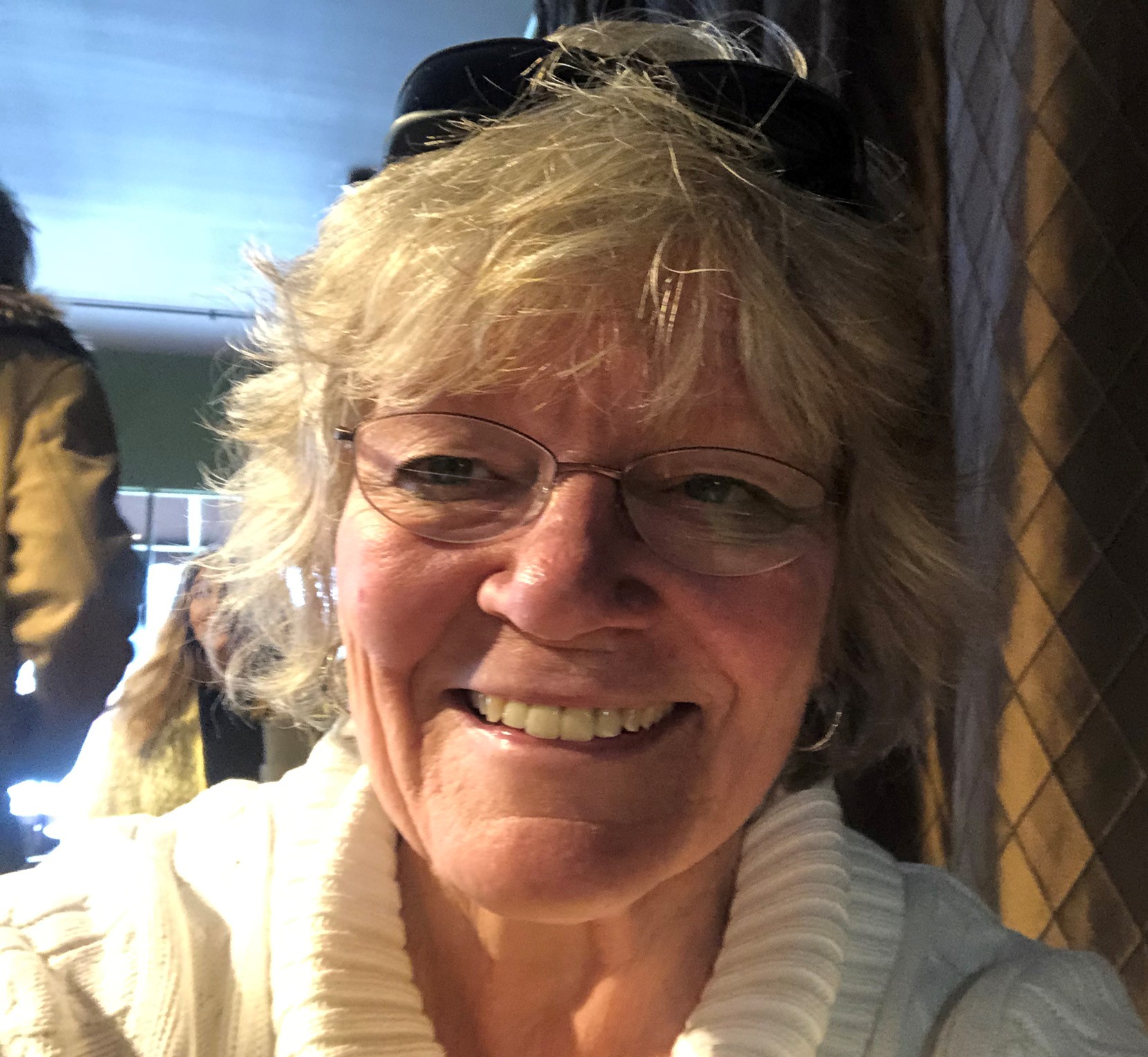 Snapshot of middle aged woman (graying with glasses) grinning in the sunshine.